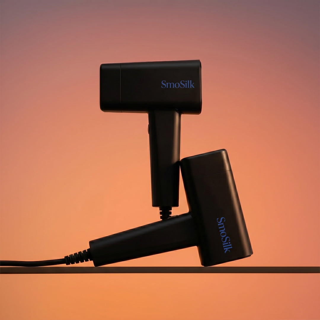 Two SmoSilk IPL devices resting on a warm neutral surface in evening light